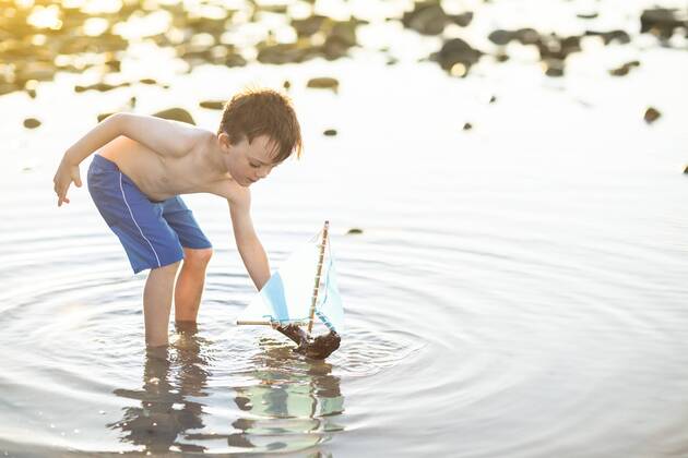 Boy playing with a toy wooden boat in the water model released Symbolfoto  ZEF003423