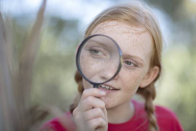South Africa, Girl on field trip looking through magnifying glass model released Symbolfoto  ZEF003929