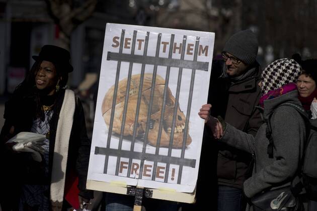 Gedenkmarsch Kolonialgeschichte DEU, Deutschland, Germany, Berlin, 27.02.2016 Demonstranten mit Plakat Voelkermord verjaehrt nicht und Set them Free beim 10. Gedenkmarsch zur Erinnerung an die afrikanischen Opfer von Versklavung, Kolonialismus und rassistischer Gewalt vom Komitee fuer ein afrikanisches Denkmal in Berlin und afrikanischer Vereine in Berlin. Dieser Gedenkmarsch wurde ins Leben gerufen, um der Forderung nach Anerkennung der Verbrechen gegen Schwarze Menschen und Menschen afrikanischer Herkunft Nachdruck zu verleihen. Anlass ist die Berliner Afrika-Konferenz von 1884 - 1885, auf der Afrika vor 130 Jahren unter den europaeischen Kolonialmaechten aufgeteilt wurde. Mehr als 30 Millionen Afrikanerinnen und Afrikaner wurden Opfer von Versklavung und kolonialen Verbrechen gegen die Menschlichkeit. Die von Deutschland an den Herero und Nama begangenen Voelkermorde in Namibia und di