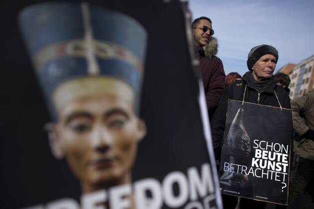 Gedenkmarsch Kolonialgeschichte DEU, Deutschland, Germany, Berlin, 27.02.2016 Demonstrant mit Plakat Freedom of Movement Schon Beutekunst betrachtet und Foto der Nofretete gegen die Kolobialgeschichte und die Aneigung afrikanischer Kulturgueter durch deutsche Museen und dem Humboldt Forum beim 10. Gedenkmarsch zur Erinnerung an die afrikanischen Opfer von Versklavung, Kolonialismus und rassistischer Gewalt vom Komitee fuer ein afrikanisches Denkmal in Berlin und afrikanischer Vereine in Berlin. Dieser Gedenkmarsch wurde ins Leben gerufen, um der Forderung nach Anerkennung der Verbrechen gegen Schwarze Menschen und Menschen afrikanischer Herkunft Nachdruck zu verleihen. Anlass ist die Berliner Afrika-Konferenz von 1884 - 1885, auf der Afrika vor 130 Jahren unter den europaeischen Kolonialmaechten aufgeteilt wurde. Mehr als 30 Millionen Afrikanerinnen und Afrikaner wurden Opfer von Verskla