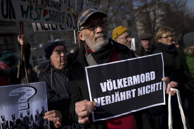 Gedenkmarsch Kolonialgeschichte DEU, Deutschland, Germany, Berlin, 27.02.2016 Demonstranten mit Plakat Voelkermord verjaehrt nicht und Set them Free beim 10. Gedenkmarsch zur Erinnerung an die afrikanischen Opfer von Versklavung, Kolonialismus und rassistischer Gewalt vom Komitee fuer ein afrikanisches Denkmal in Berlin und afrikanischer Vereine in Berlin. Dieser Gedenkmarsch wurde ins Leben gerufen, um der Forderung nach Anerkennung der Verbrechen gegen Schwarze Menschen und Menschen afrikanischer Herkunft Nachdruck zu verleihen. Anlass ist die Berliner Afrika-Konferenz von 1884 - 1885, auf der Afrika vor 130 Jahren unter den europaeischen Kolonialmaechten aufgeteilt wurde. Mehr als 30 Millionen Afrikanerinnen und Afrikaner wurden Opfer von Versklavung und kolonialen Verbrechen gegen die Menschlichkeit. Die von Deutschland an den Herero und Nama begangenen Voelkermorde in Namibia und di