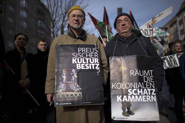 Gedenkmarsch Kolonialgeschichte DEU, Deutschland, Germany, Berlin, 27.02.2016 Demonstrant mit Plakat Preussischer Kulturbesitz und raeumt die kolonialen Schatzkamamern gegen die Kolobialgeschichte und die Aneigung afrikanischer Kulturgueter durch deutsche Museen und dem Humboldt Forum beim 10. Gedenkmarsch zur Erinnerung an die afrikanischen Opfer von Versklavung, Kolonialismus und rassistischer Gewalt vom Komitee fuer ein afrikanisches Denkmal in Berlin und afrikanischer Vereine in Berlin. Dieser Gedenkmarsch wurde ins Leben gerufen, um der Forderung nach Anerkennung der Verbrechen gegen Schwarze Menschen und Menschen afrikanischer Herkunft Nachdruck zu verleihen. Anlass ist die Berliner Afrika-Konferenz von 1884 - 1885, auf der Afrika vor 130 Jahren unter den europaeischen Kolonialmaechten aufgeteilt wurde. Mehr als 30 Millionen Afrikanerinnen und Afrikaner wurden Opfer von Versklavung