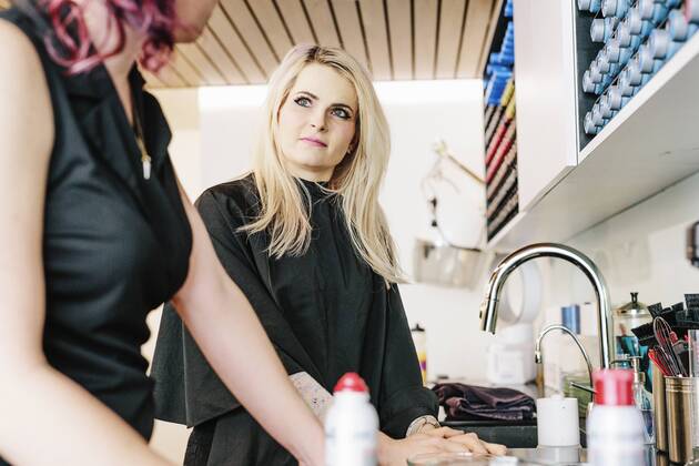 A hair stylist and a client, a young woman with long blonde hair, at a hair salon. A hair stylist and a client, a young woman with long blonde hair, at a hair salon. 21693