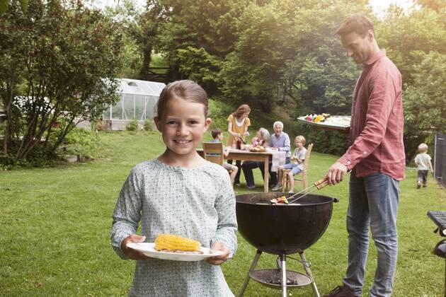 Grillen mit der Familie - Model Released Smiling girl holding plate with corn cob on a family barbecue model released Symbolfoto property released  RBF004773