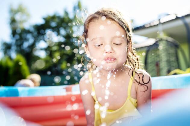 Little girl sitting in paddling pool splashing with water model released Symbolfoto property released  HAPF000759