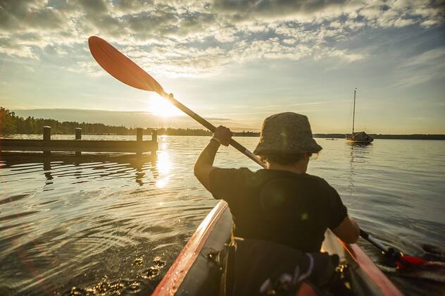 Eine Frau fährt mit ihrem Kajak auf dem Starnberger See dem Sonnenuntergang entgegenan, Starnberg, Bayern, Deutschland. Eine Frau paddelt auf einer Kajaktour auf dem Starnberger See
