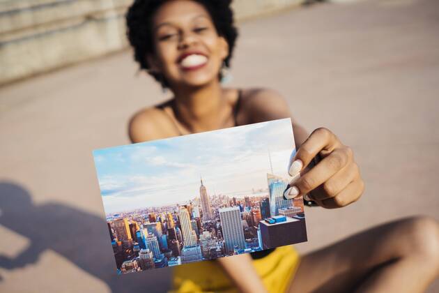 Youniverse - Young Holidays Happy woman showing postcard of New York City model released Symbolfoto property released  GIOF001429