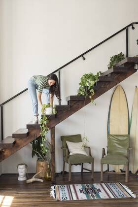 Young woman on stairs in a loft caring for potted plant model released Symbolfoto property released  WESTF22099