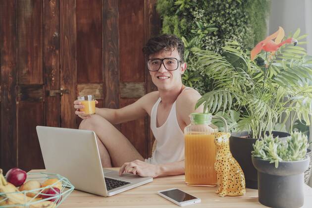 Young man using laptop and drinking orange juice at home model released Symbolfoto  RTBF00826