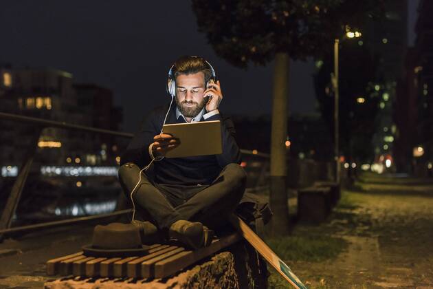 Young man with tablet and headphones in the city at night model released Symbolfoto  UUF10891