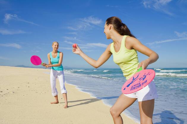 Two young women having fun at the beach and playing beach ball together  A5