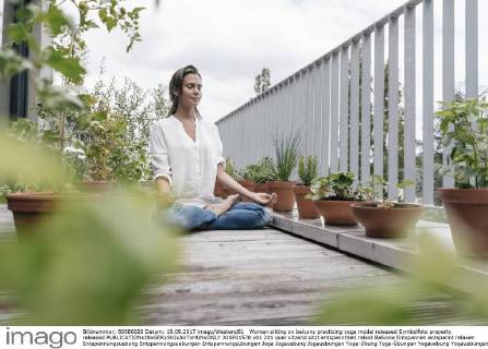 Woman sitting on balcony practicing yoga model released Symbolfoto property released  JOSF01578