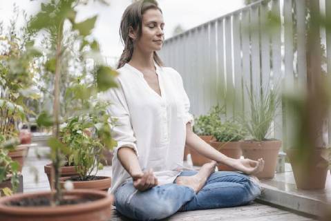 Woman sitting on balcony practicing yoga model released Symbolfoto property released  JOSF01640