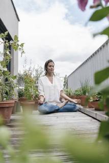 Woman sitting on balcony practicing yoga model released Symbolfoto property released  JOSF01579