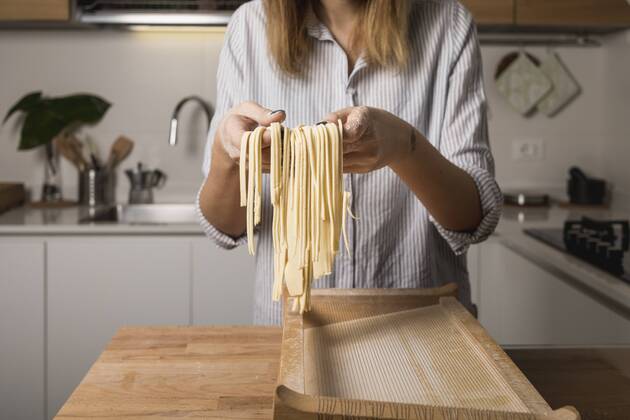 Woman preparing homemade pasta, holding row noodles, pasta harp model released Symbolfoto property released  MAUF01262