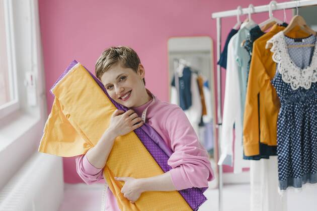 Portrait of smiling tailoress holding textiles model released Symbolfoto property released  KNSF03292