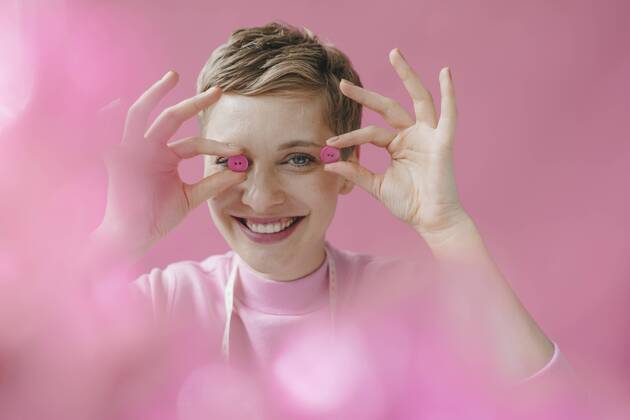 Portrait of happy tailoress holding pink buttons model released Symbolfoto property released  KNSF03300