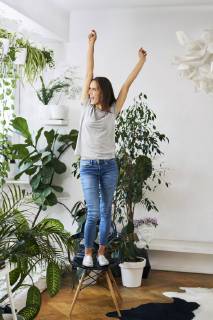 Young woman standing on chair in a room cheering model released Symbolfoto property released  BSZF00161