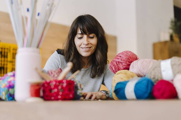 Smiling woman at table with knitting model released Symbolfoto property released  OCAF00036