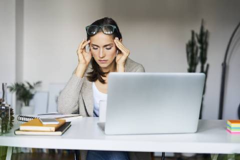 Young woman at home with laptop on desk touching her temples model released Symbolfoto property released  BSZF00168