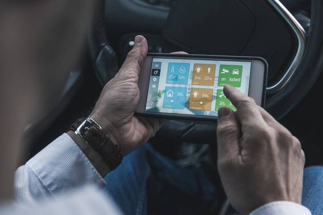 Man in car adjusting devices at home via smartphone model released Symbolfoto property released  UUF12651