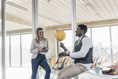 Woman looking at businessman balancing basketball in office model released Symbolfoto property released  UUF13118