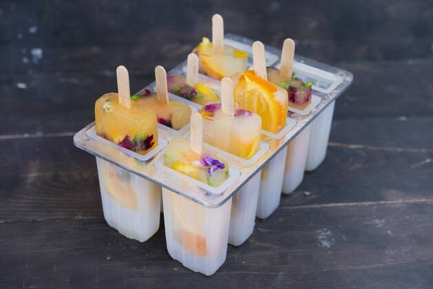 Homemade orange and lemon popsicles with edible flowers  SKCF00442