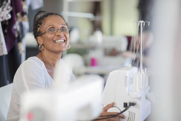 Portrait of happy seamstress with sewing machine model released Symbolfoto property released  ZEF15336
