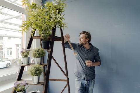 Man with glass of coffee and paint brush looking out of window model released Symbolfoto property released  JOSF02159