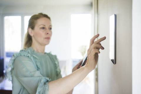 Woman adjusting digital tablet mounted on wall with smartphone model released Symbolfoto property released  MOEF01056