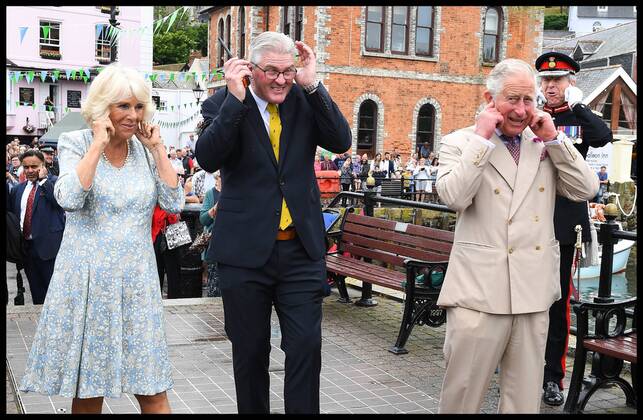 . 16 07 2018. Fowey, United Kingdom. Prince Charles the Duchess of Cornwall visit Cornwall. The Duke and Duchess of Cornwall put their fingers in their ears as the cannon gun is fired to launch the gig race as they visit the celebration of Fowey festival meeting local businesses, representatives from Fowey gig club and members of the RNLI on Fowey Quay.  xAndrewxParsonsx xi-Imagesx IIM-18220-0018