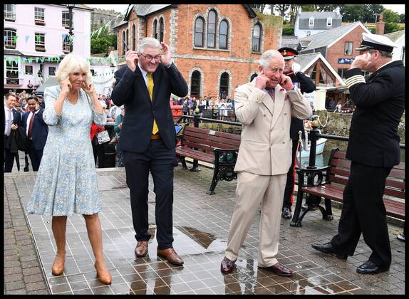 . 16 07 2018. Fowey, United Kingdom. Prince Charles the Duchess of Cornwall visit Cornwall. The Duke and Duchess of Cornwall put their fingers in their ears as the cannon gun is fired to launch the gig race as they visit the celebration of Fowey festival meeting local businesses, representatives from Fowey gig club and members of the RNLI on Fowey Quay.  xAndrewxParsonsx xi-Imagesx IIM-18220-0019
