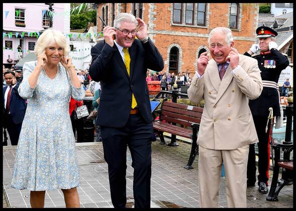 . 16 07 2018. Fowey, United Kingdom. Prince Charles the Duchess of Cornwall visit Cornwall. The Duke and Duchess of Cornwall put their fingers in their ears as the cannon gun is fired to launch the gig race as they visit the celebration of Fowey festival meeting local businesses, representatives from Fowey gig club and members of the RNLI on Fowey Quay.  xAndrewxParsonsx xi-Imagesx IIM-18220-0024
