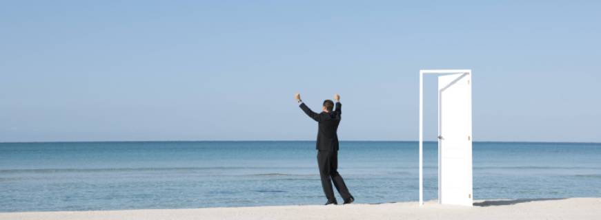 Businessman standing on beach looking at ocean with arms raised, rear view  Copyright: MilenaxBoniek B94190110