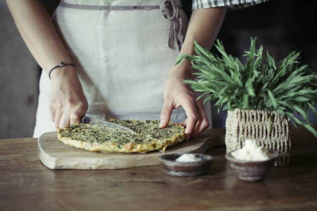Young woman slicing homemade chickpea and herb cake model released Symbolfoto  ALBF00424