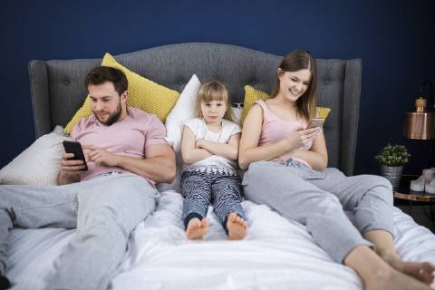 Neglected little girl sitting on bed with her parents, using smartphones model released Symbolfoto property released  AWF00042