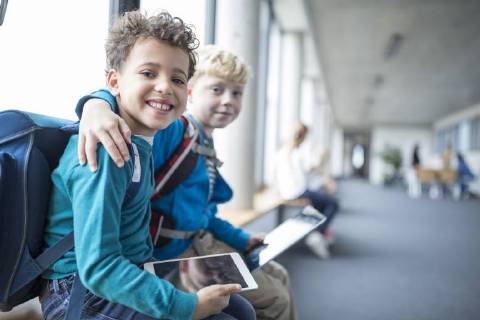 IMAGO Creative: Gesellschaft, Integration Portrait of two smiling schoolgboys with tablet embracing model released Symbolfoto property released  WESTF24179