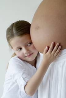 Girl embracing mother s pregnant belly  Copyright: FrédéricxCirou B09759514