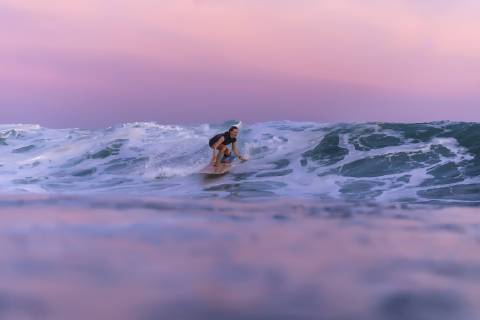 Distant view of single young woman surfing in sea at sunset, Kuta Lombok Indonesia TRKO020221 model released Symbolfoto Copyright: KonstantinxTrubavin TRKO020221