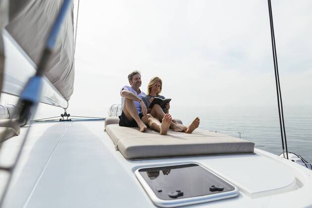 Couple sitting on deck of catamaran, relaxing, woman reading book model released Symbolfoto property released  EBSF02603