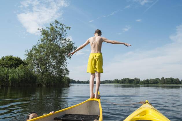 Rear view of boy jumping from canoe in lake  Copyright: SvenxHagolani fStopImages1473016
