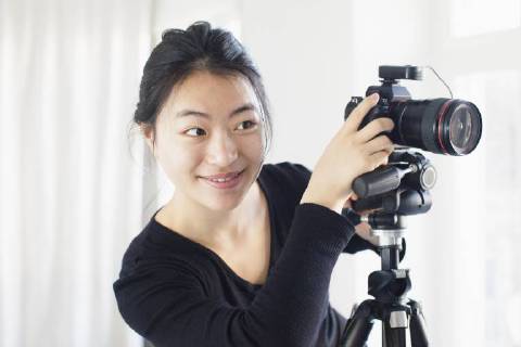 Smiling young woman photographing with camera  Copyright: RalfxHiemisch fStopImages1735007