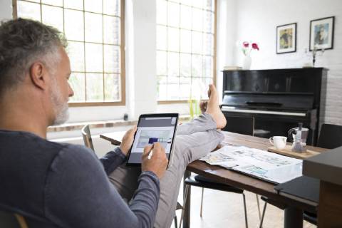 Mature man working from his home office with feet up, using tablet model released Symbolfoto property released  FKF03042
