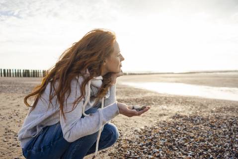 Redheaded woman collecting shell on the beach model released Symbolfoto  KNSF04273