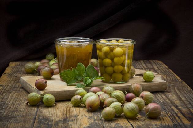 Jar of gooseberry jam, gooseberries and glass of preserved gooseberries on wood  LVF06270