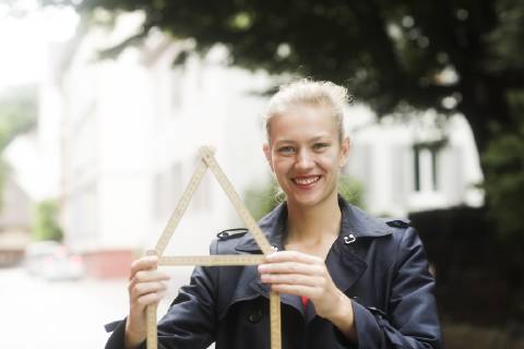 Portrait of smiling young woman holding pocket rule shaped like a house model released Symbolfoto  SGF02196