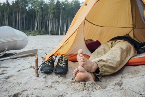 Man lying in tent on beach model released Symbolfoto  VPIF00424