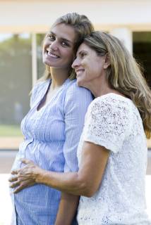 Mother putting hand on pregnant daughter s stomach  Copyright: EricxAudras B78940518