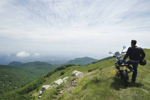 Man standing by motorcycle on top of mountain, rear view  Copyright: FrédéricxCirou B95963710
