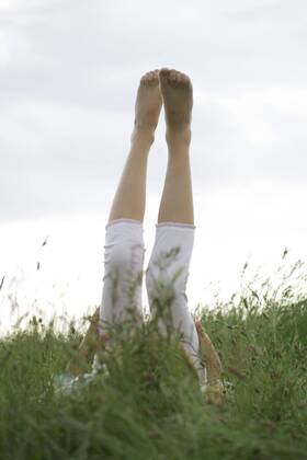 Girl lyingon back in tall grass with legs raised in the air  Copyright: LaurencexMouton B99066016